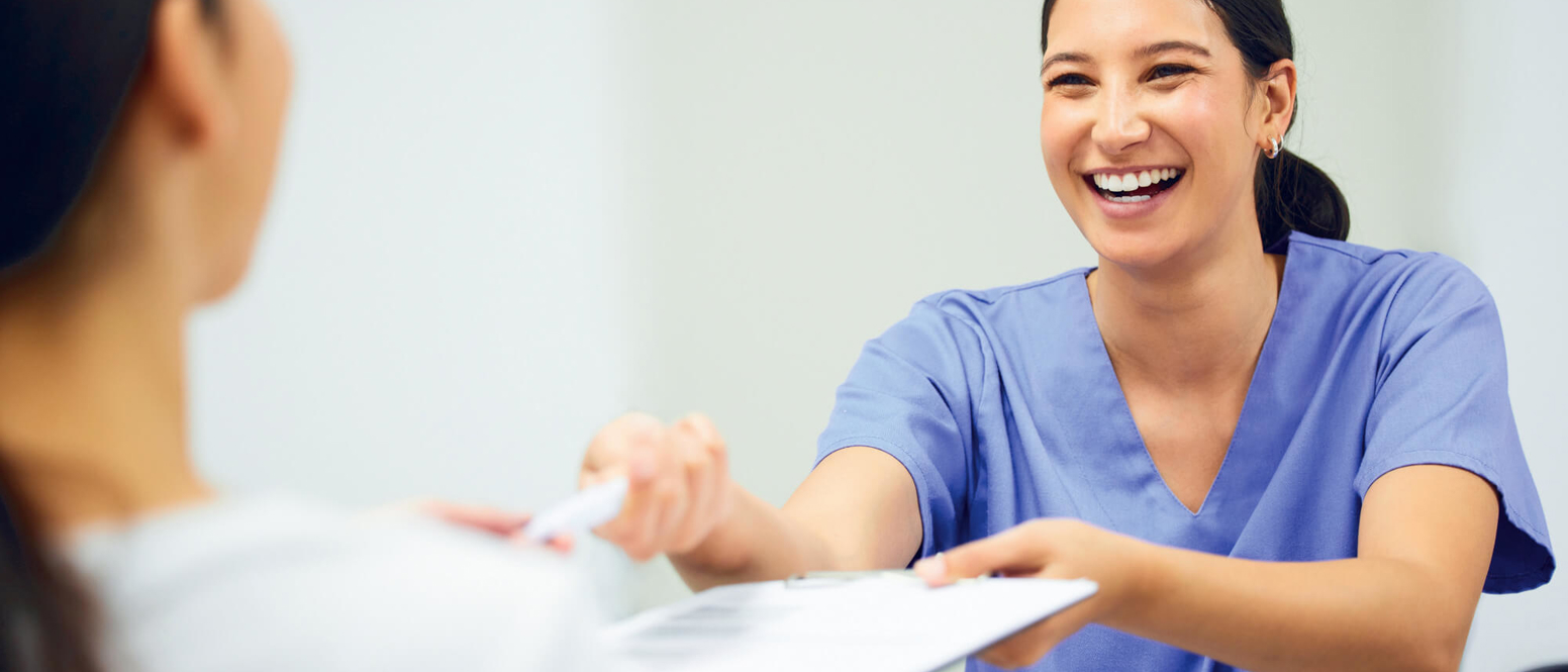 Lady in scrubs passing clipboard to someone